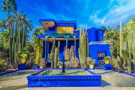 a blue house with a fountain and cacti