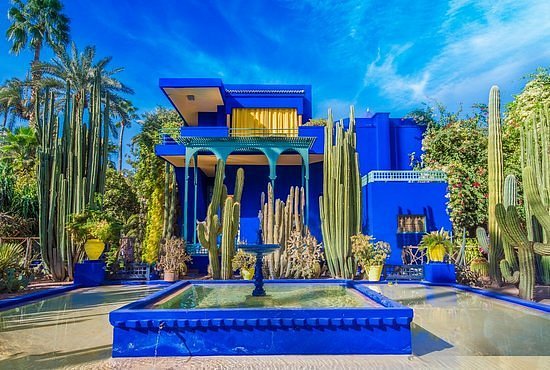 a blue house with a fountain and cacti